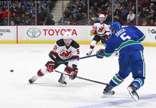 VANCOUVER, BC - JANUARY 15: Luca Sbisa #5 of the Vancouver Canucks takes a shot past Taylor Hall #9 of the New Jersey Devils during their NHL game at Rogers Arena January 15, 2017 in Vancouver, British Columbia, Canada. (Photo by Jeff Vinnick/NHLI via Getty Images)